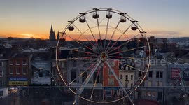 Christmas Ferris Wheel in Cork City, Ireland at Sunset overlooking St Fin Barre's cathedral in freezing temperatures