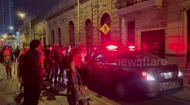 Anti government protesters in Lima force police car to reverse after it tries to pass location where protesters was injured by projectile earlier in the night