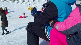 Slo-mo footage of children sledding colliding with unsuspecting woman
