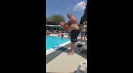 Fun-loving adult tries diving through a tube floating in pool