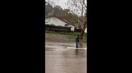 Man paddleboards across flooded neighbourhood in California, US