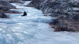 Man slides down frozen waterfall in China