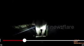 Protective mother elephant trumpets at passing motorist when escorting baby across road