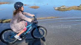 King tide massive flooding -  family rides bikes on the path in Sausalito, CA which has become inundated with water due to the king tide