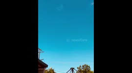 Silver orb hurtling across a blue sky at just a few hundred feet.