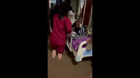 Indonesian nurses wheel patient through knee-deep floodwater as medical centre becomes inundated