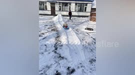 Elderly Chinese woman uses snow to build slide for great-grandson