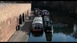 A single lady walking past some boats on the Regents Canal, London, United Kingdom