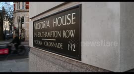 Cyclists speeding through London and the Victoria House, 37-63 Southampton Row, United Kingdom