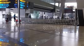 Workers push dozens of bundled trolleys into the luggage room at Indonesian airport