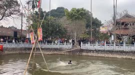 People join the challenge of crossing the bamboo bridge over the river to receive rewards
