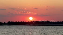 Sunset over a lake in Oklahoma with birds flying and a boat going by