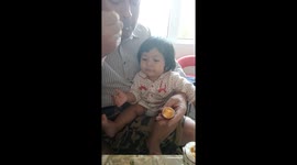 A cute 7 month old baby is being fed some solid foods for the first time she loves egg so much that she suddenly grabs the spoon.