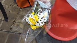 Crash scene on Kensington High Street cordoned off with traffic lights bent and flower tributes for the victim