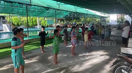 Schoolchildren practice arm strokes and flutter kicks during swimming lesson in Vietnam