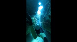 Scuba divers navigate through tight sun lit canyons in the Belize Barrier Reef