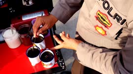 Indonesian police officer hands out free coffee to locals whilst on his patrols