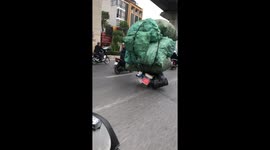 Severely overloaded motorbikes covered with huge cargo sacks