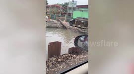 Amusing little boys ride colourful inflatables in flooded drain