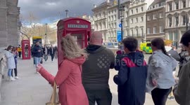 Tourists queue up to get their photo taken with iconic red telephone boxes in London