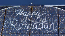 A tiny crescent moon appears above the Ramadan lights in London's West End