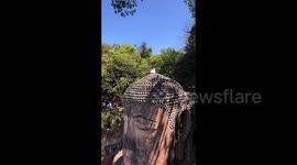 Woman causes a stir by climbing and meditating on the head of China's Leshan Giant Buddha