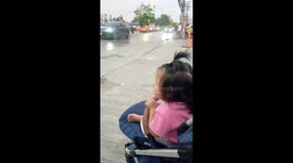 A little 8 months old baby in a stroller watching Somgkran festival water splashing in Thailand.
