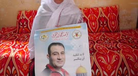 Palestinian woman Khadra al-Burai, 80, holds pictures of her son, Nidal al-Burai, who has been imprisoned in Israeli prisons for 28 years, on the Palestinian Prisoner's Day