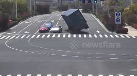 Terrifying moment container truck flips over at intersection, narrowly missing 3 cars