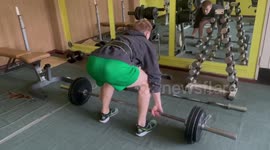 A guy lifts a 100 kg or 222 LBS barbell at the gym