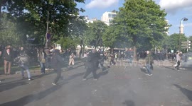 Police officers chased out of park by protesters during May Day rally in Paris