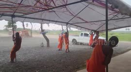 Buddhist monks hold onto tent during storm in Thailand