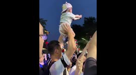 Chinese Father Enlists Baby's Help to Capture Stunning Night View Amidst Crowded Tourist Spot