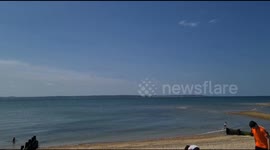 Plane flys low over the seaside on Portsmouth beach in the sunshine