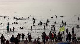 Palestinians gather on the beach in Gaza City during a heat wave