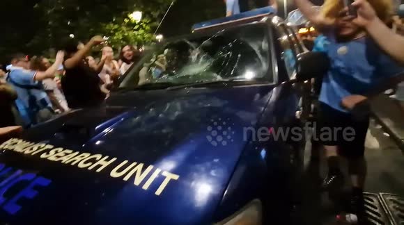 Man City fans bounce up and down on top of police car in city centre