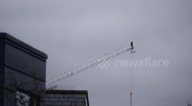 Tower Crane engineer navigates precariously along a crane jib employed in building an apartment development at 'One Pentire