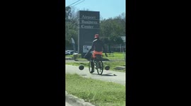 Witness the spectacle of a man skillfully juggling basketballs while cycling through the streets of Florida