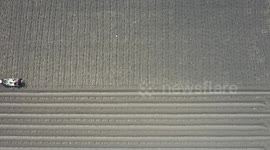 The farmer is using the machine to do farming, the video is shot with a drone, the scene is beautiful shot from above like a picture.