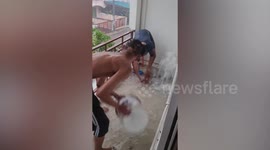 Residents battle to scoop up flood from apartment balcony