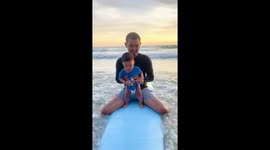 A 9 months kid who stand on the surfboard for the first time.