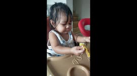 A cute girl, she is 11 months old, she eats breakfast by herself.