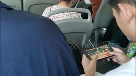 A Citizen Plays A Naruto Mobile Phone Game on A Bus in Yichang, China