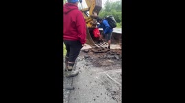 Man Uses Backhoe To Cross Washed Out Road and Bring Home Groceries