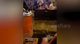 Revellers carry on drinking as bar floods during storm in Bangkok