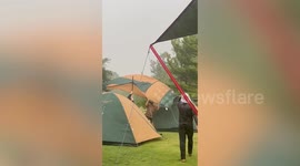 Campers battle to hold up their tents while being battered by wind and rain