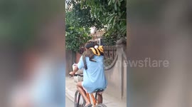 Pet cat rides on cyclist's shoulders on road in the Philippines