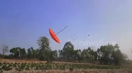 Dust devil blows umbrella across field in Thailand