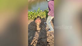 Boy stuck in sinking mud next while playing next to river in Cambodia