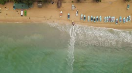 A bird's eye view captures the elegant ballet of a boat finding its haven along the undulating embrace of the sea shore